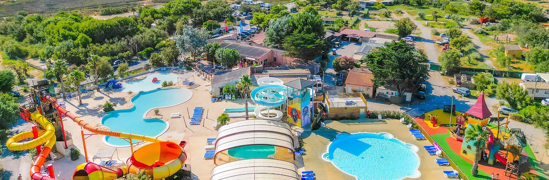 Aerial view of a campsite with pools, slides and shaded pitches