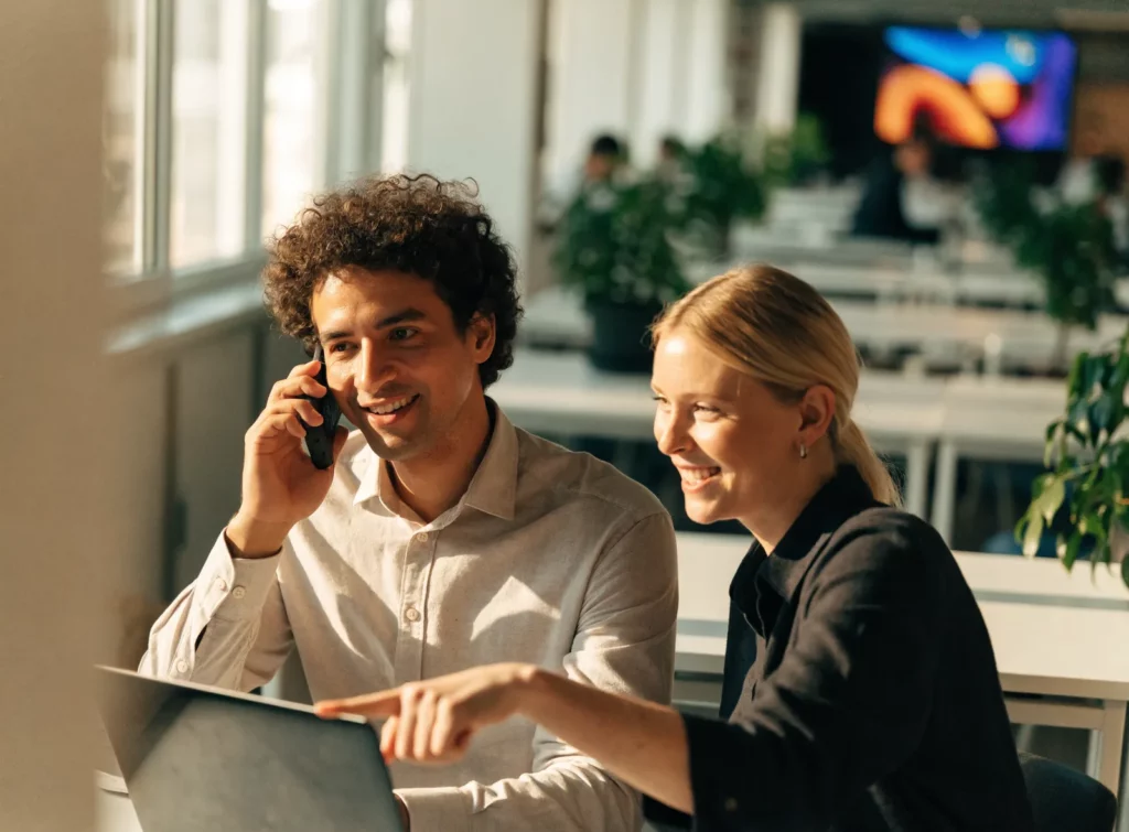 Deux collaborateurs EMITY souriants, dont l’un au téléphone avec un client
