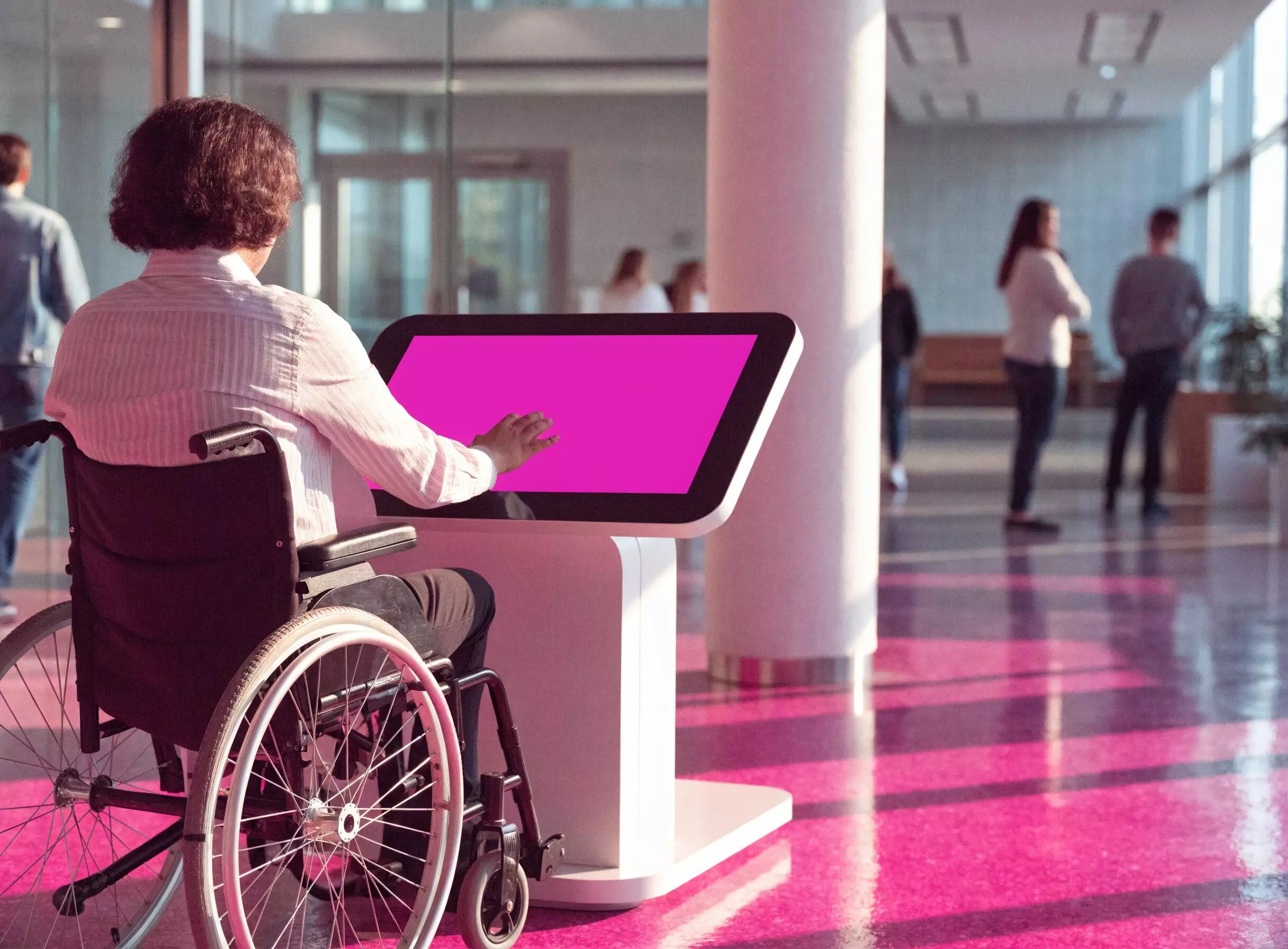 Mode PMR E-CLICK : une personne en fauteuil roulant utilise une borne tactile à interface abaissée