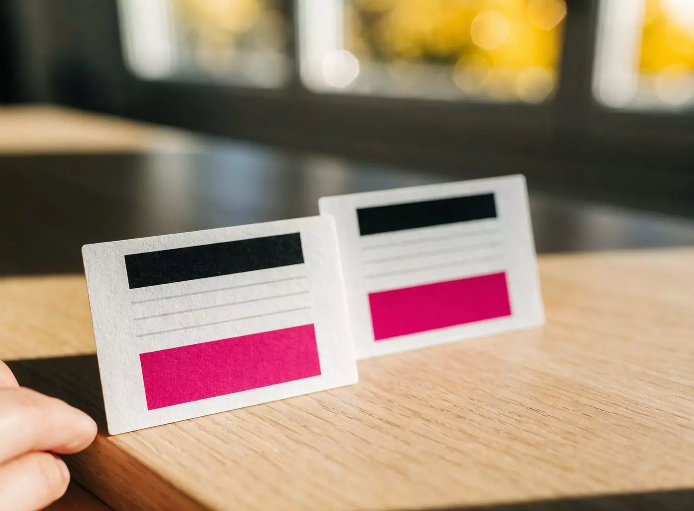 Deux petits écrans e-paper posés sur une table en bois, l'un en plein soleil et l'autre à l'ombre, tous deux parfaitement lisibles