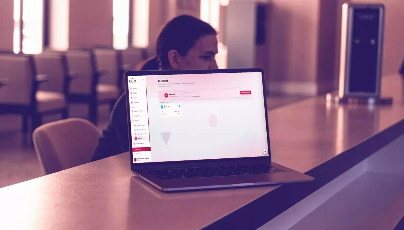 EMITY queue management software on a laptop at a reception counter