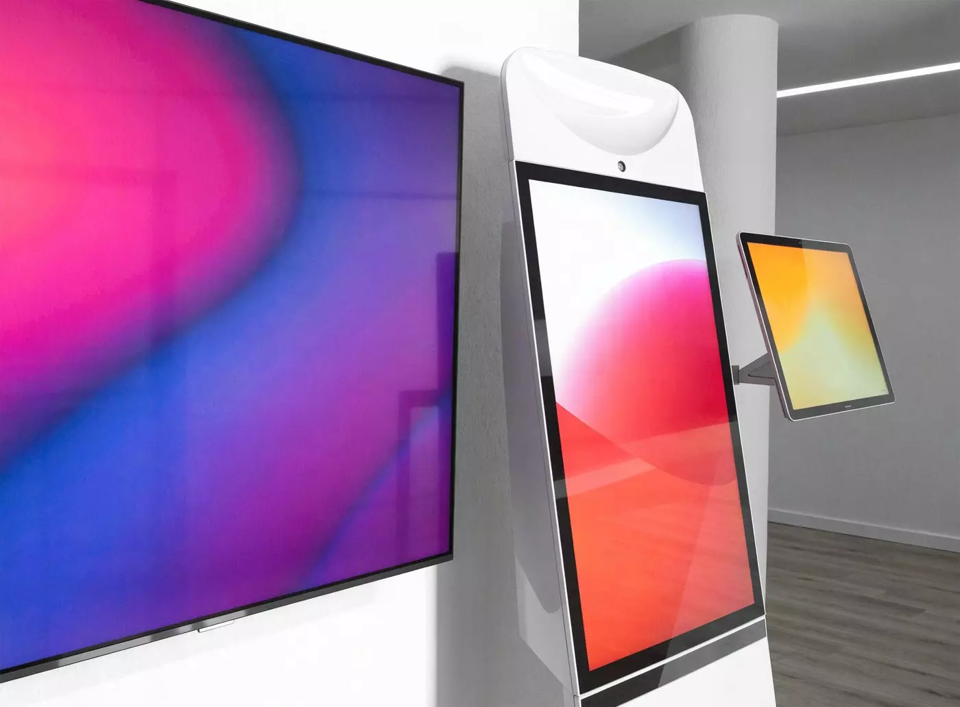 Wall screen, interactive kiosk and wall-mounted tablet switched on side by side in a showroom