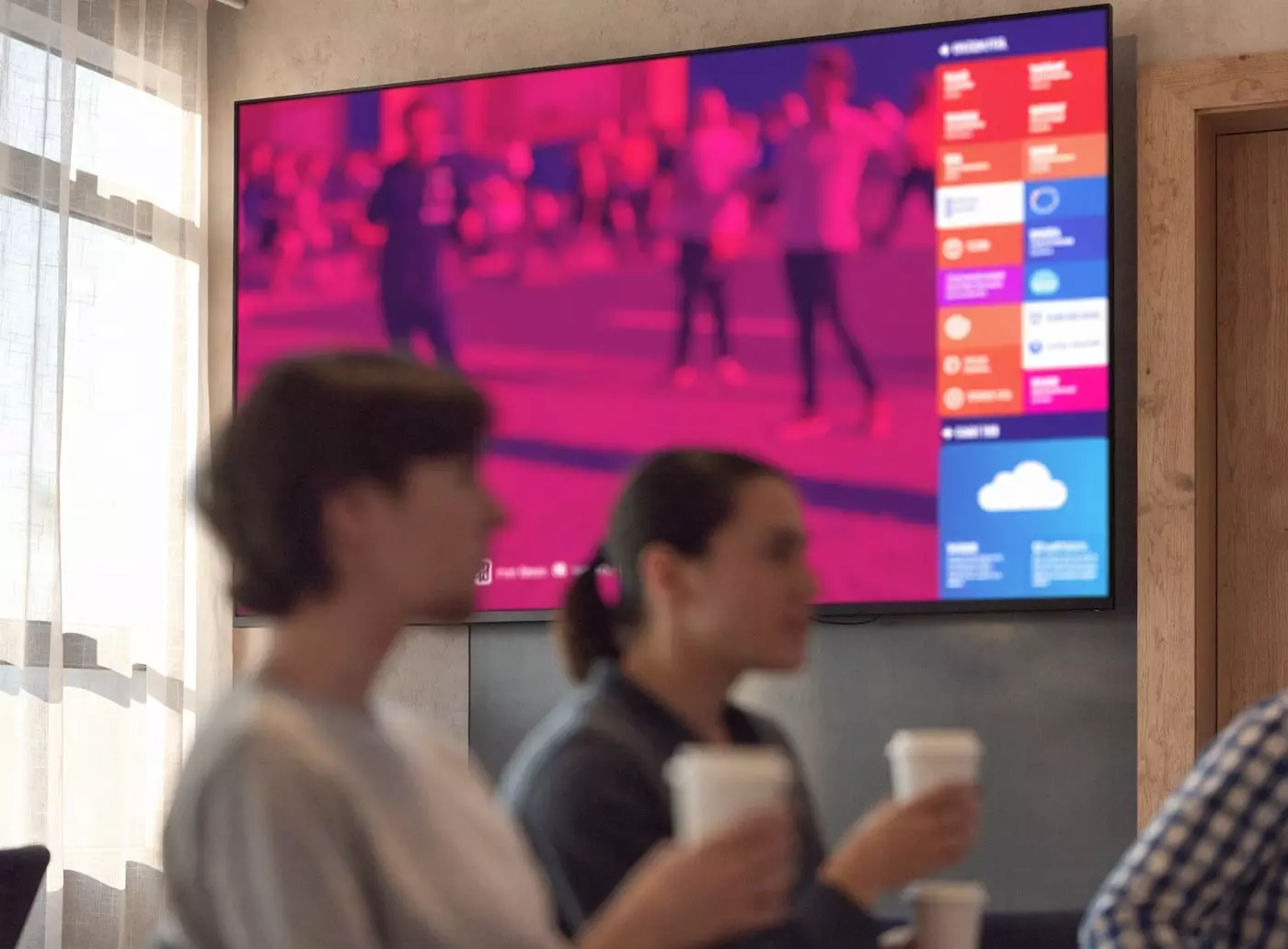 Wall screen in a company break room split between a live video and a column of information