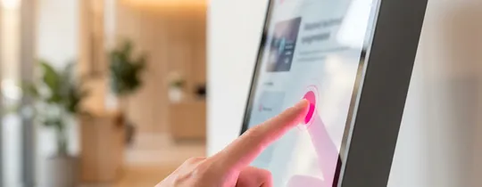 Doigt sur une borne tactile EMITY dans un hall d&rsquo;accueil