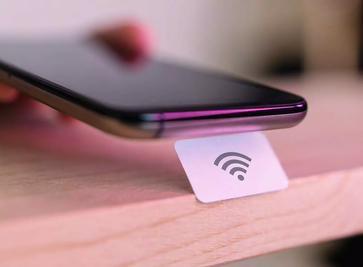 Sticker NFC tag showing the contactless pictogram, with a smartphone held a few centimeters away