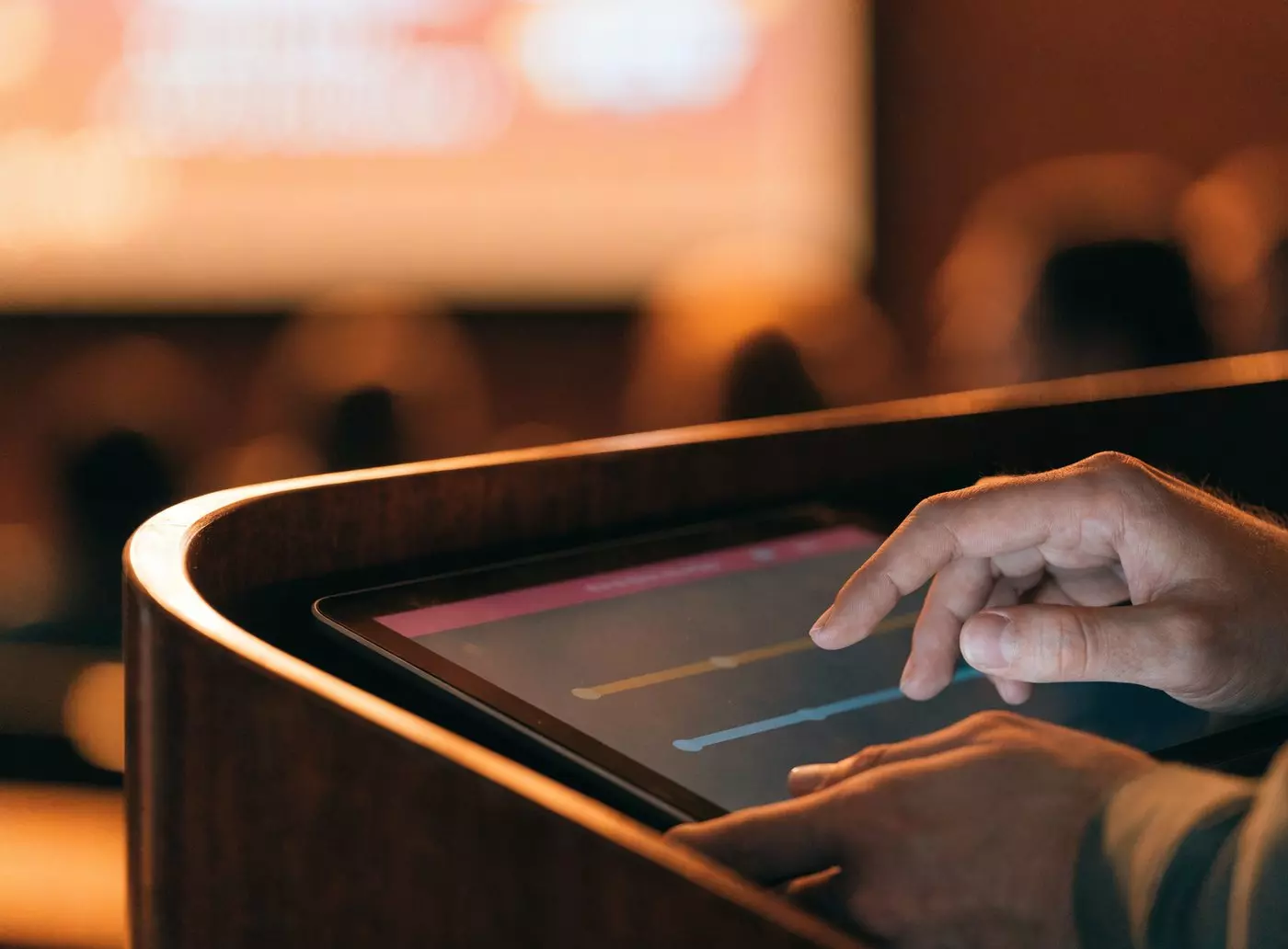 Hands on a tablet built into a lectern showing three streams to keep in sync: text, music and media