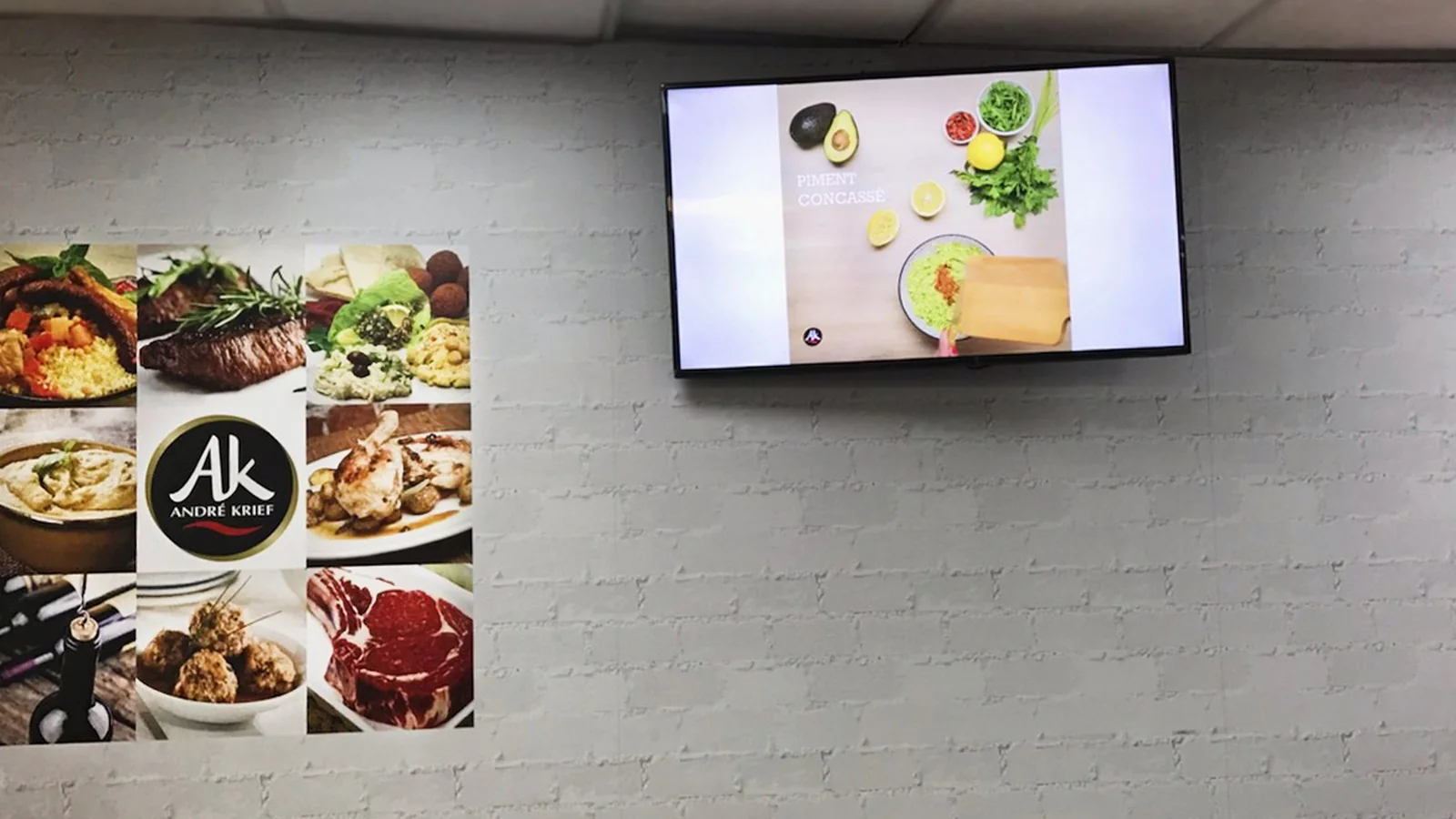 Écran mural diffusant une vidéo de recette au-dessus d'un comptoir de commerce alimentaire