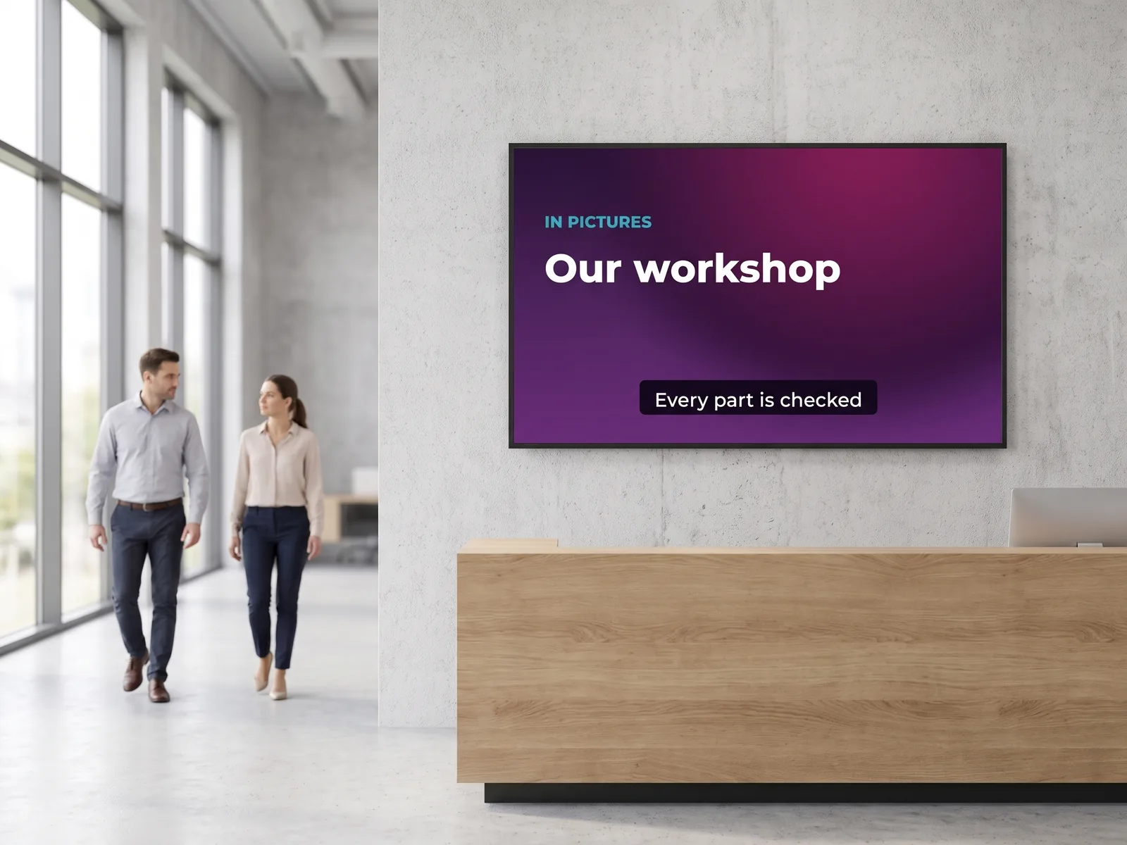 Wall-mounted screen in a company reception hall, playing a short subtitled video about the workshop