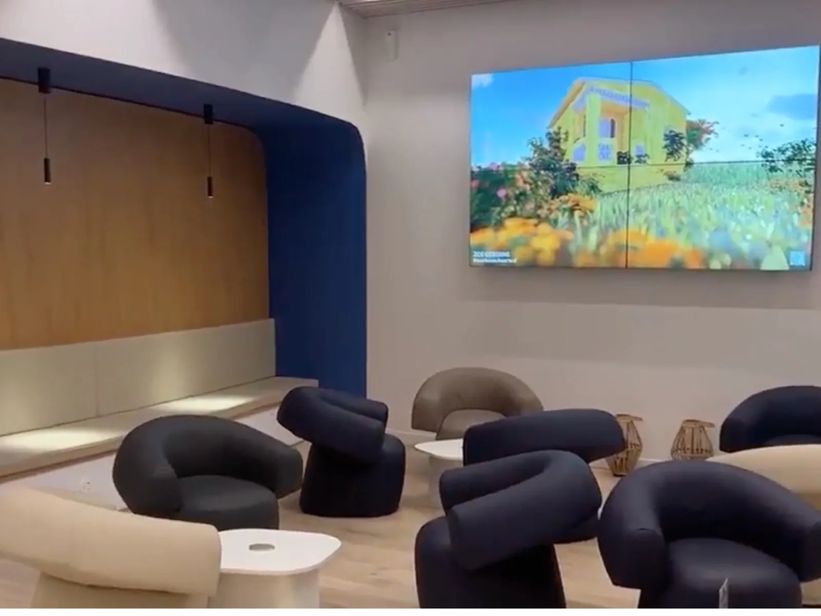 Mur de quatre &eacute;crans assembl&eacute;s diffusant une peinture de paysage dans un salon d&rsquo;a&eacute;roport aux fauteuils ronds