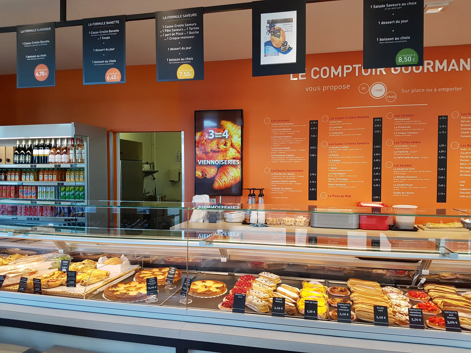 Expositor de pastisseria en una fleca Atelier Banette: una pantalla anuncia l'oferta de brioixeria sobre els éclairs i les tartaletes de fruita