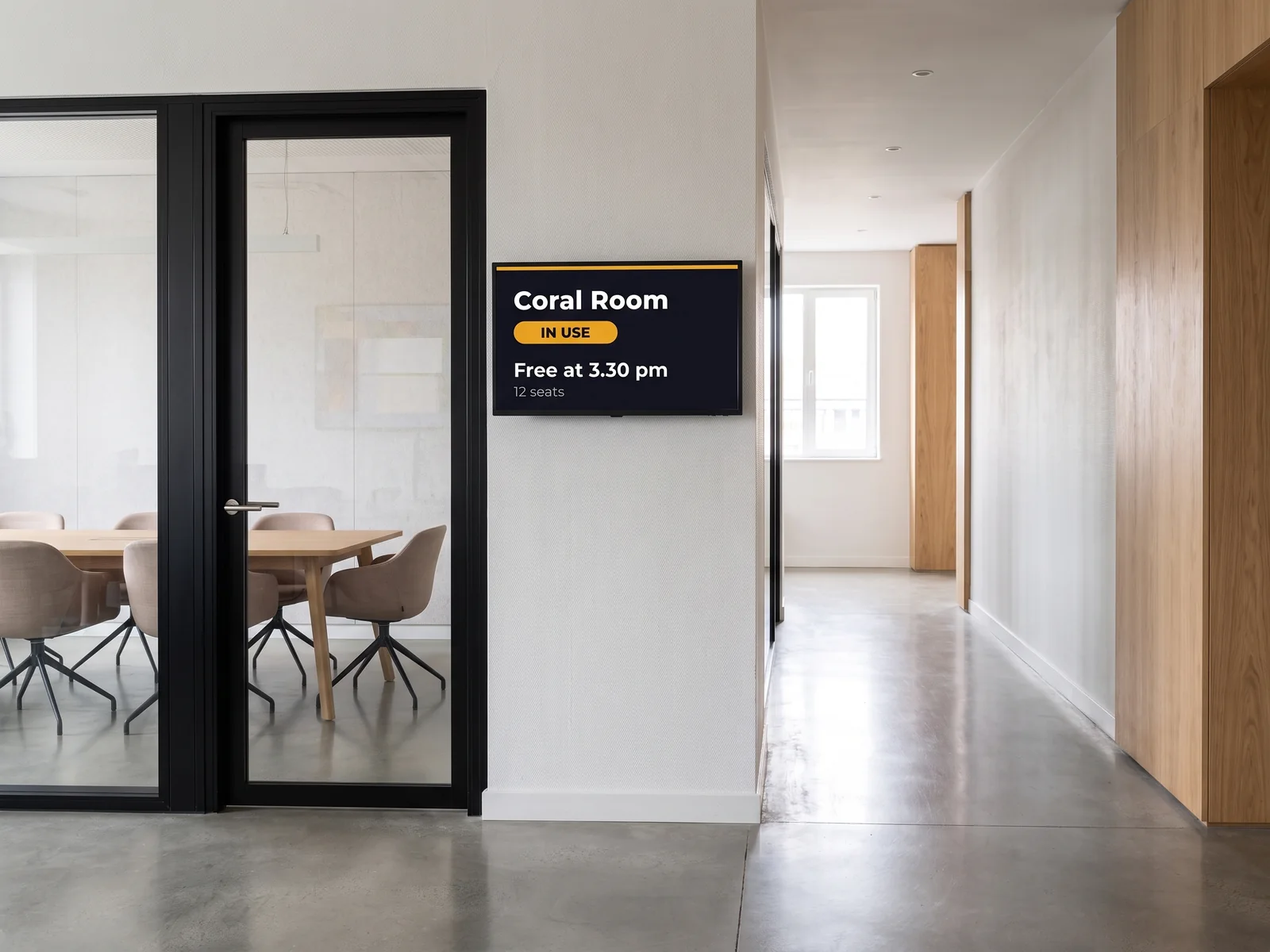 Screen beside a glazed meeting room door showing the room in use until 3.30 pm