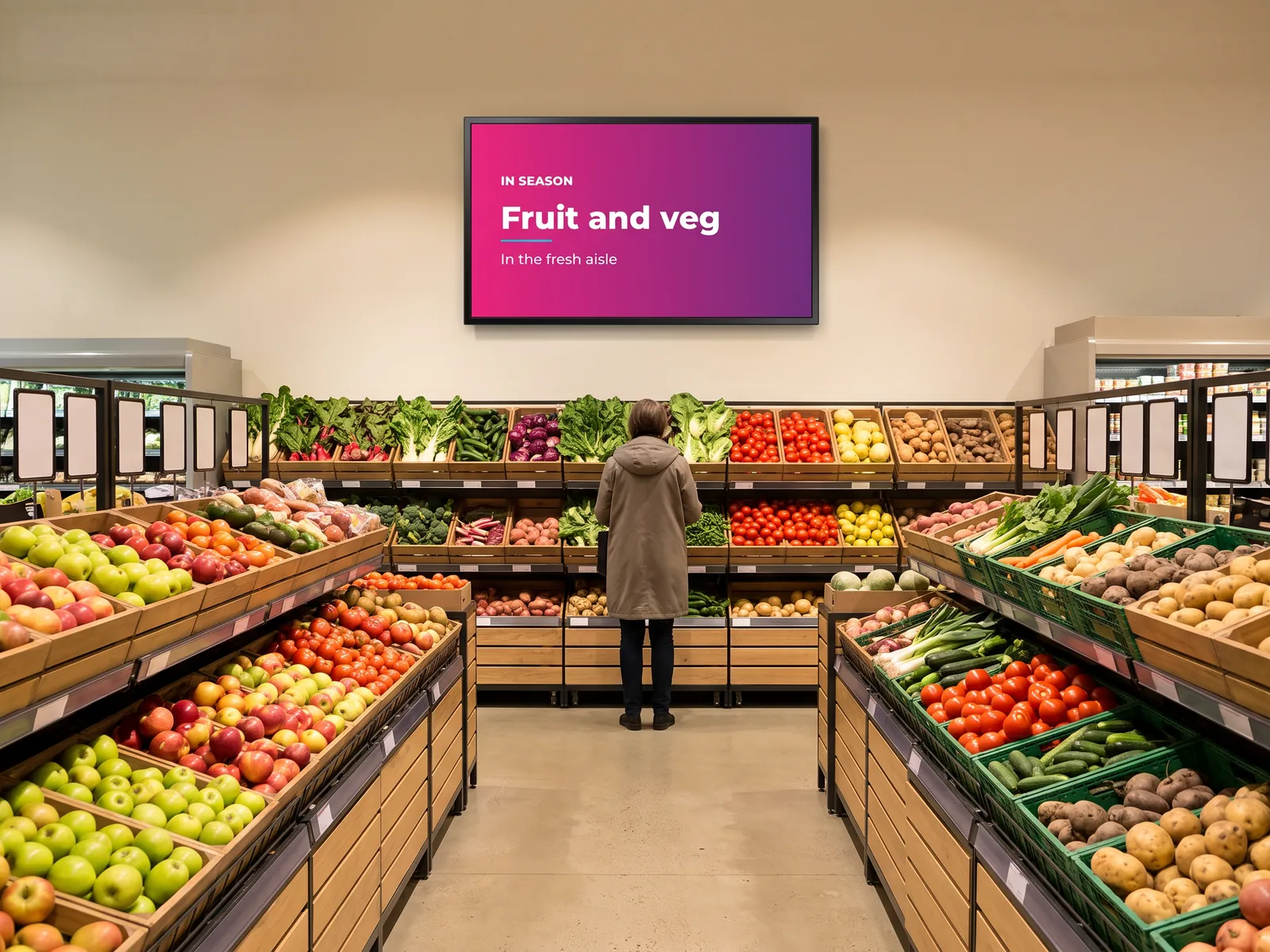 Screen above the fruit and vegetable aisle of a shop showing an in-season poster