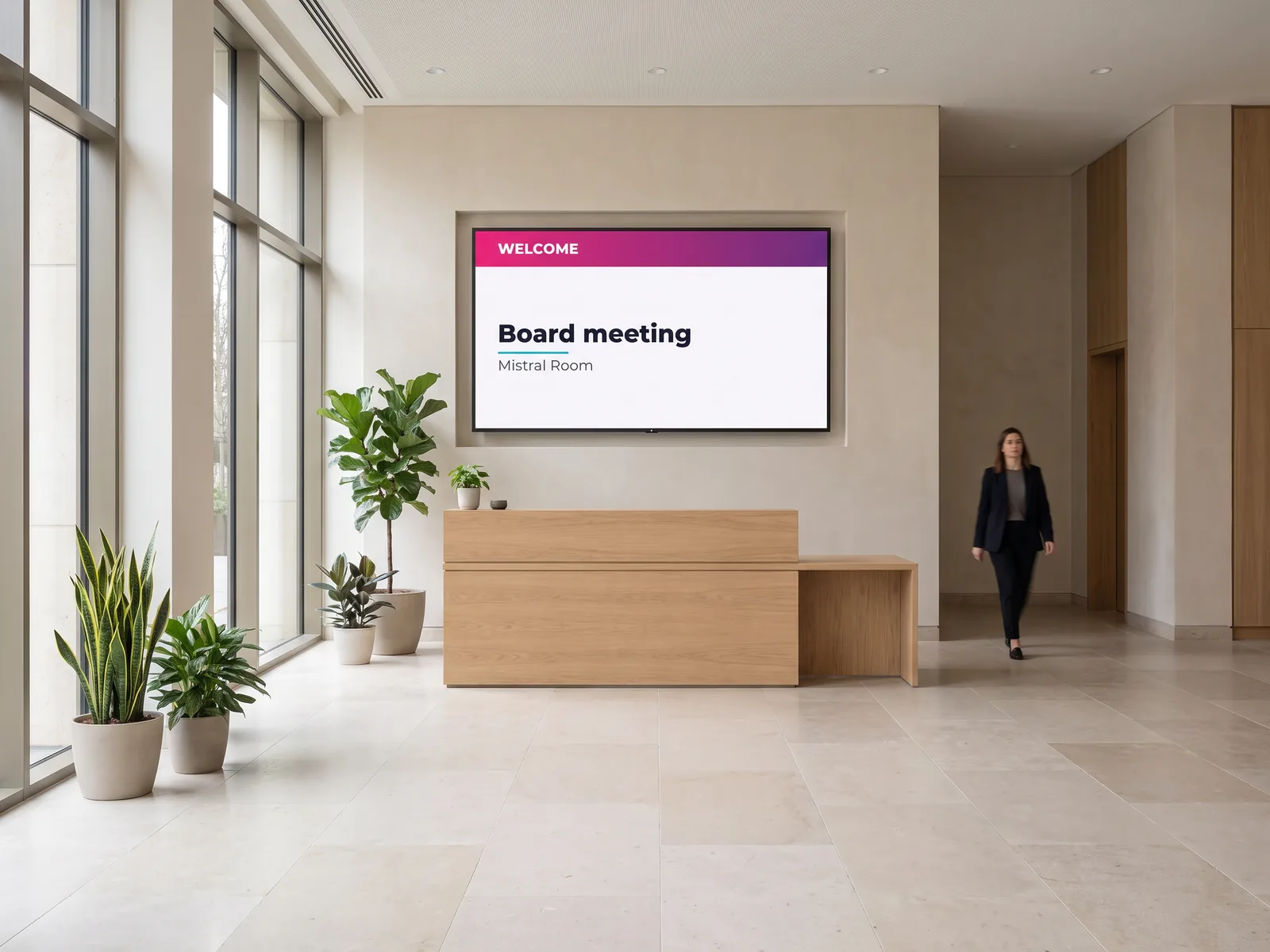 Wall-mounted screen behind an office reception desk showing a welcome message