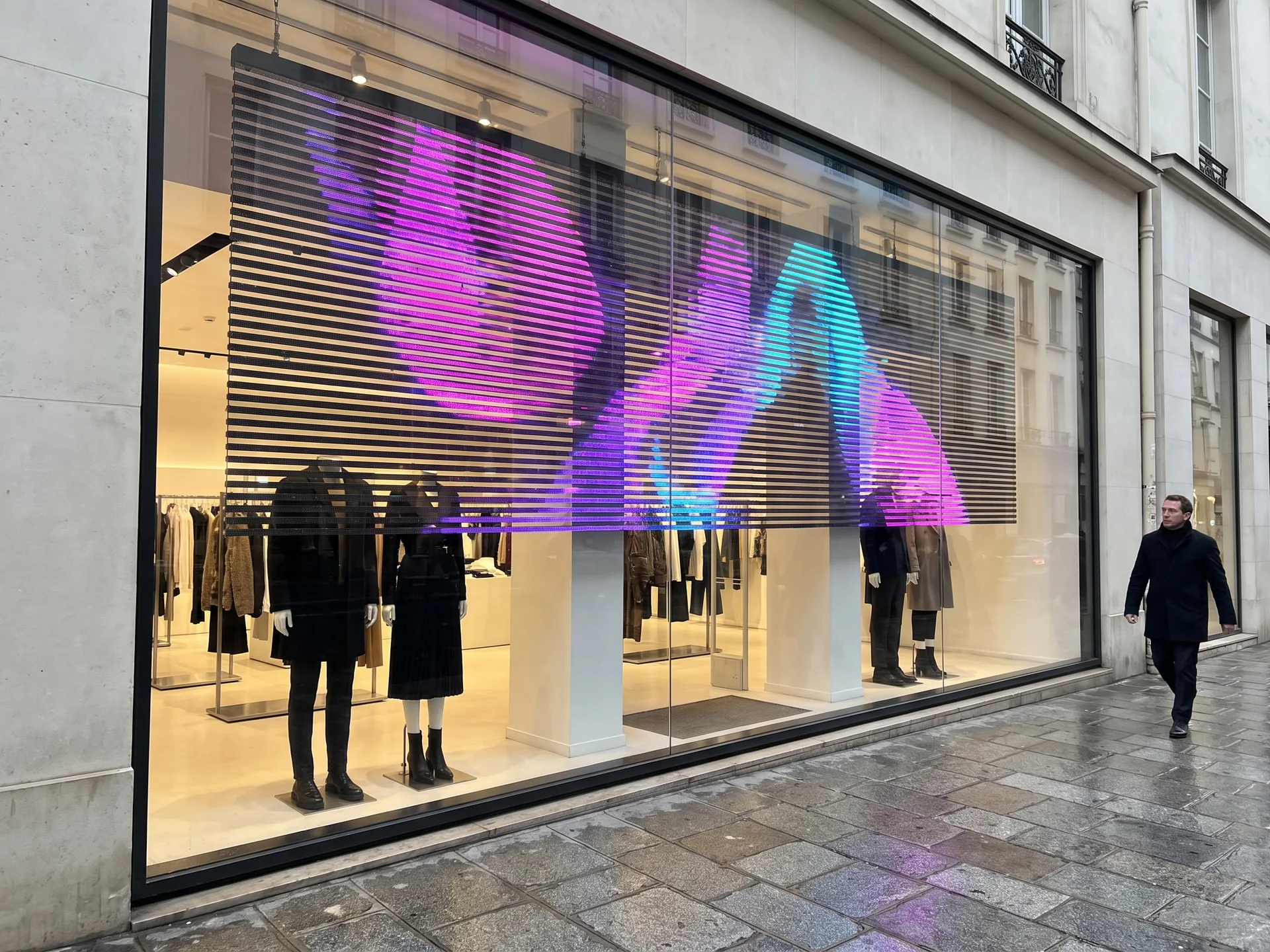 Vitrine de boutique sur rue derrière un écran LED transparent qui laisse voir le magasin