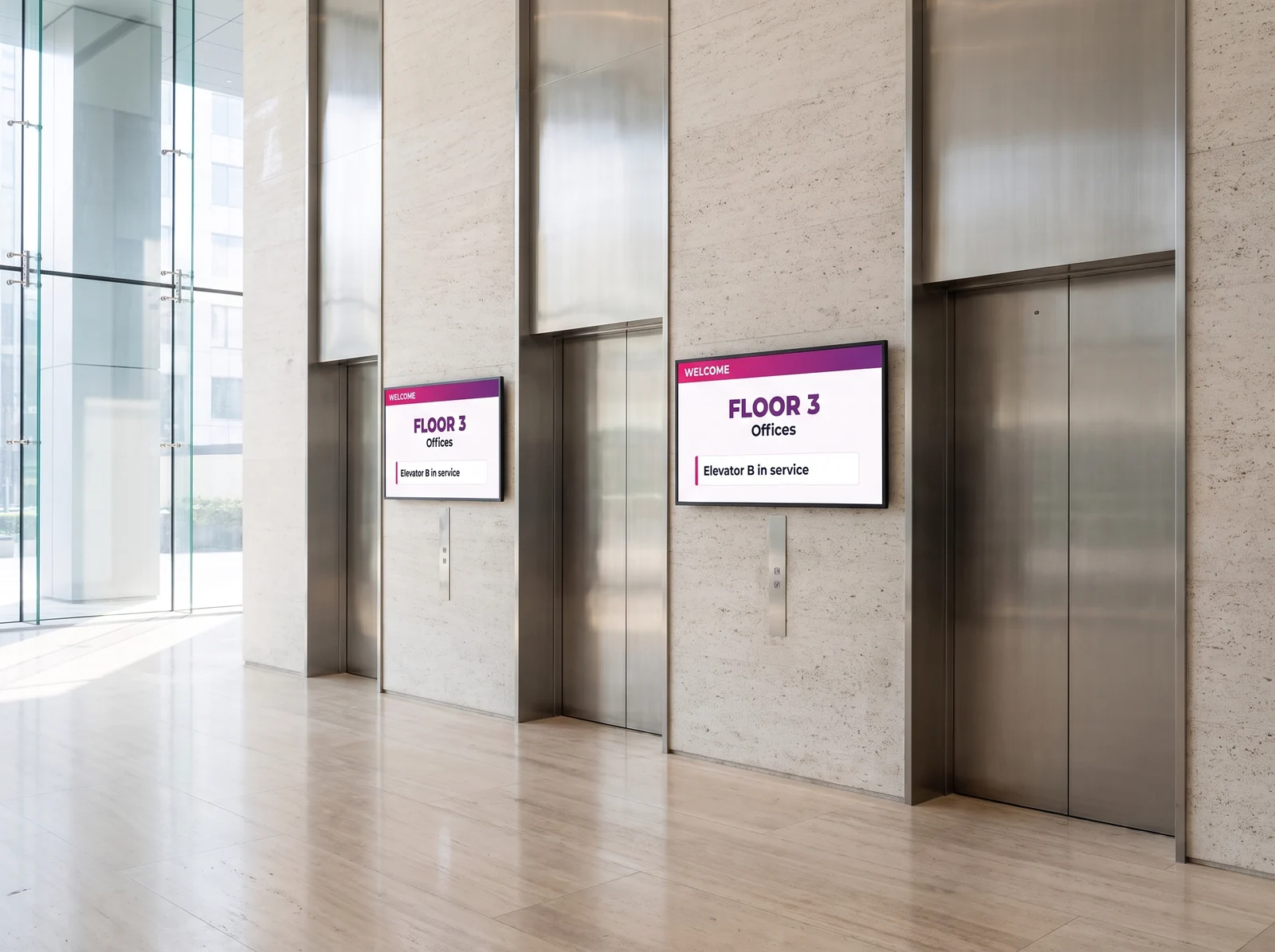 Bank of four elevators in an office tower lobby, with two wall screens showing the same information
