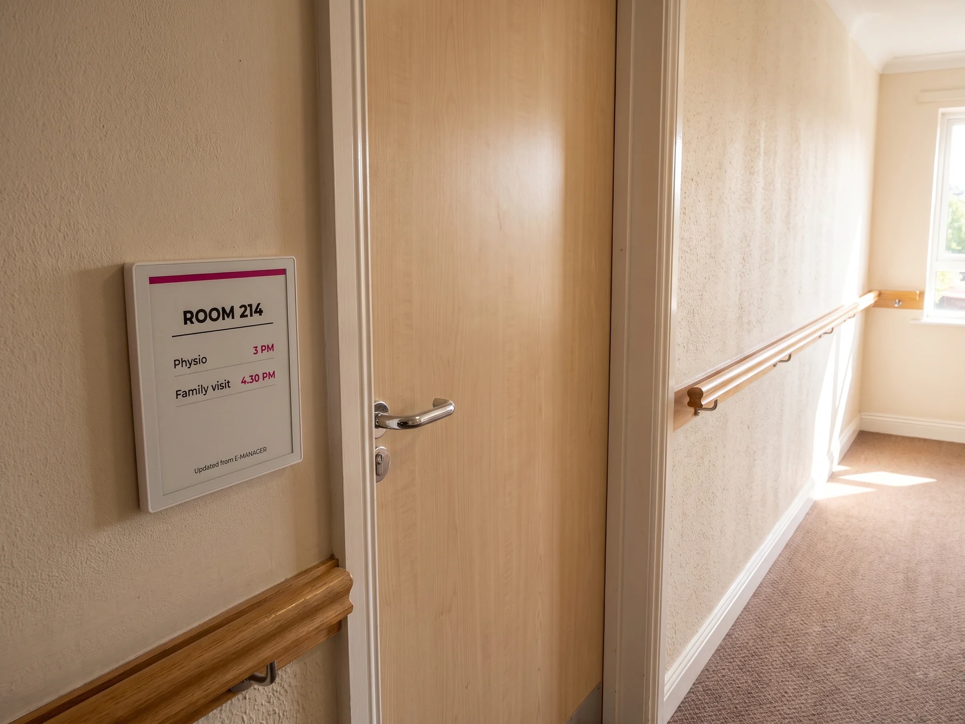 E-paper panel beside a care home bedroom door showing the room number and the day’s appointments