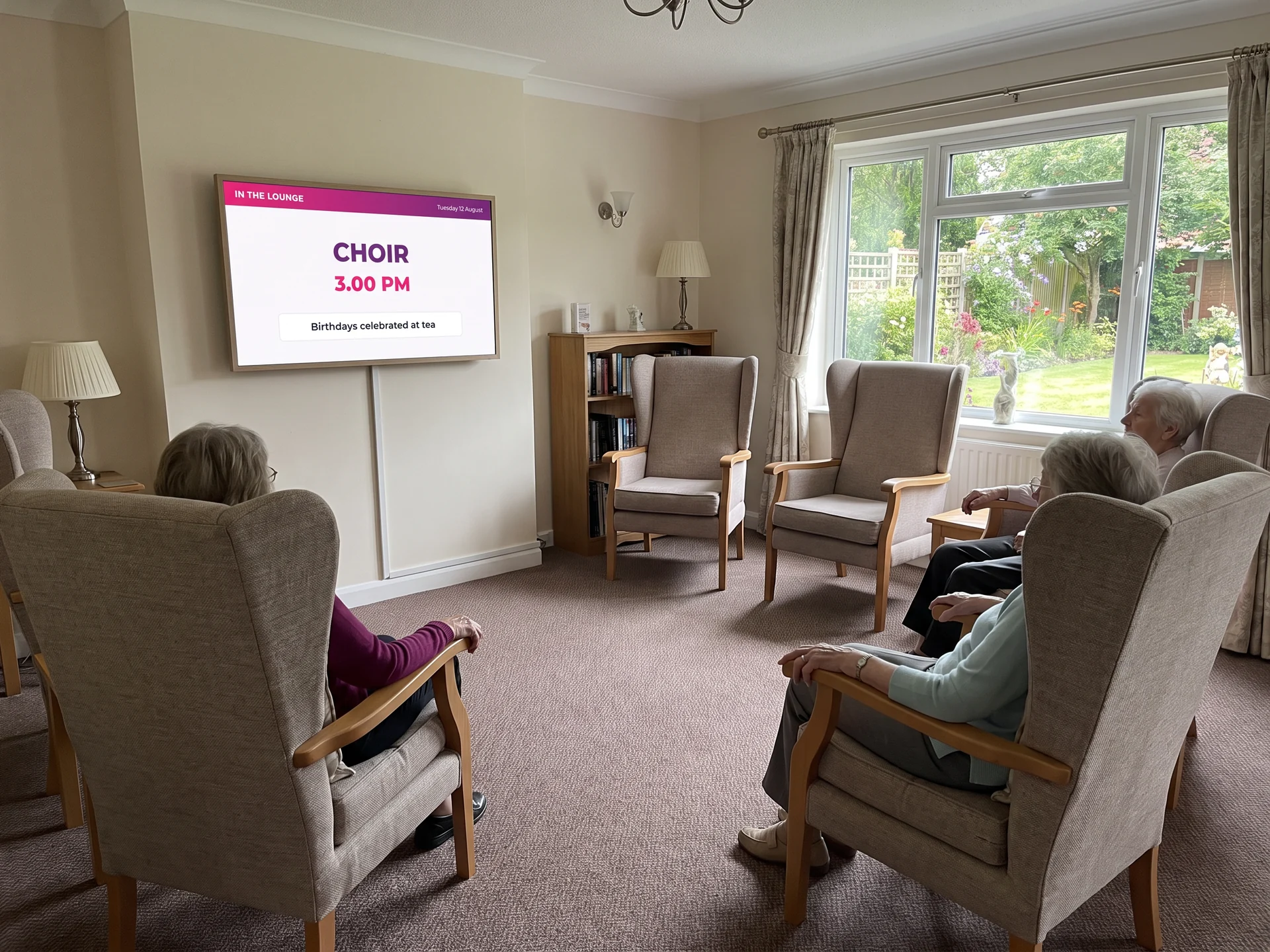 Residents seated in a care home lounge in front of a screen announcing the afternoon choir