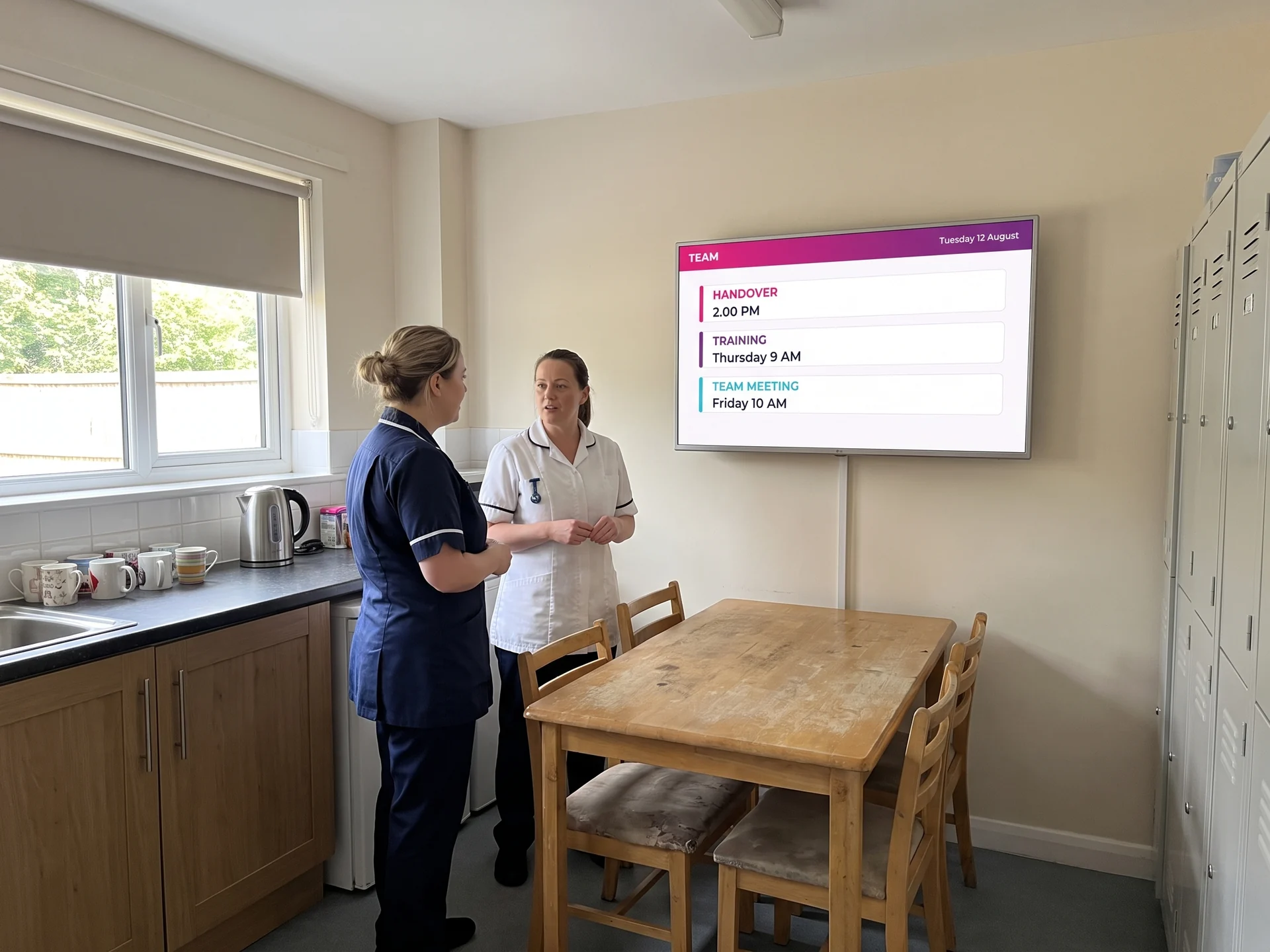 Screen in a care home staff room showing the handover time, training and the team meeting