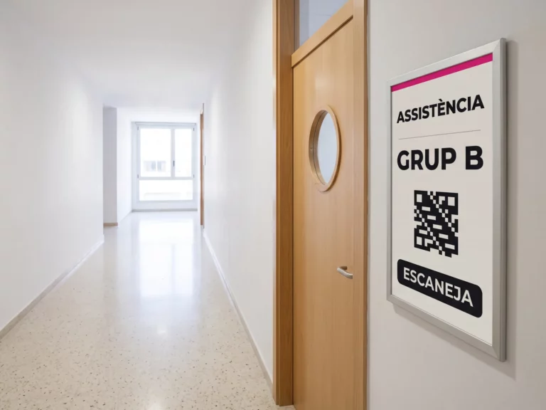 Panell de paper electrònic al costat de la porta d'una aula mostrant un codi QR per registrar l'assistència