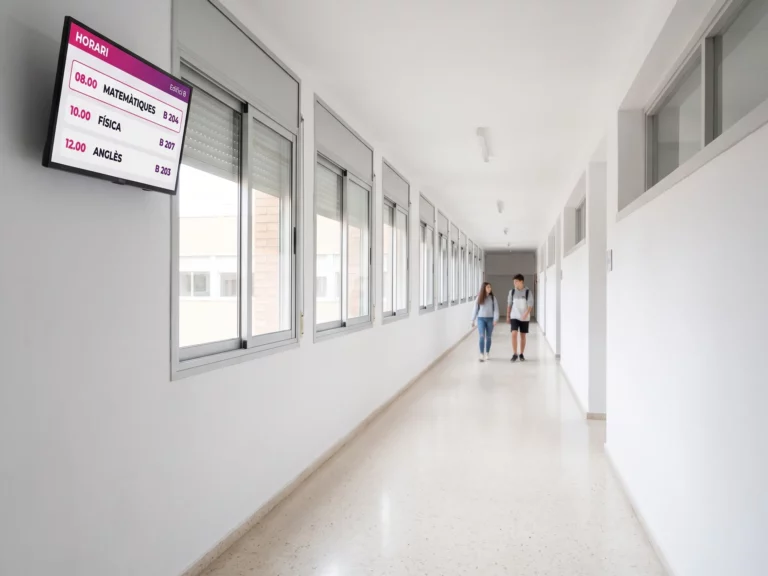 Pantalla mostrant l'horari del dia i els números d'aula al passadís d'un centre educatiu