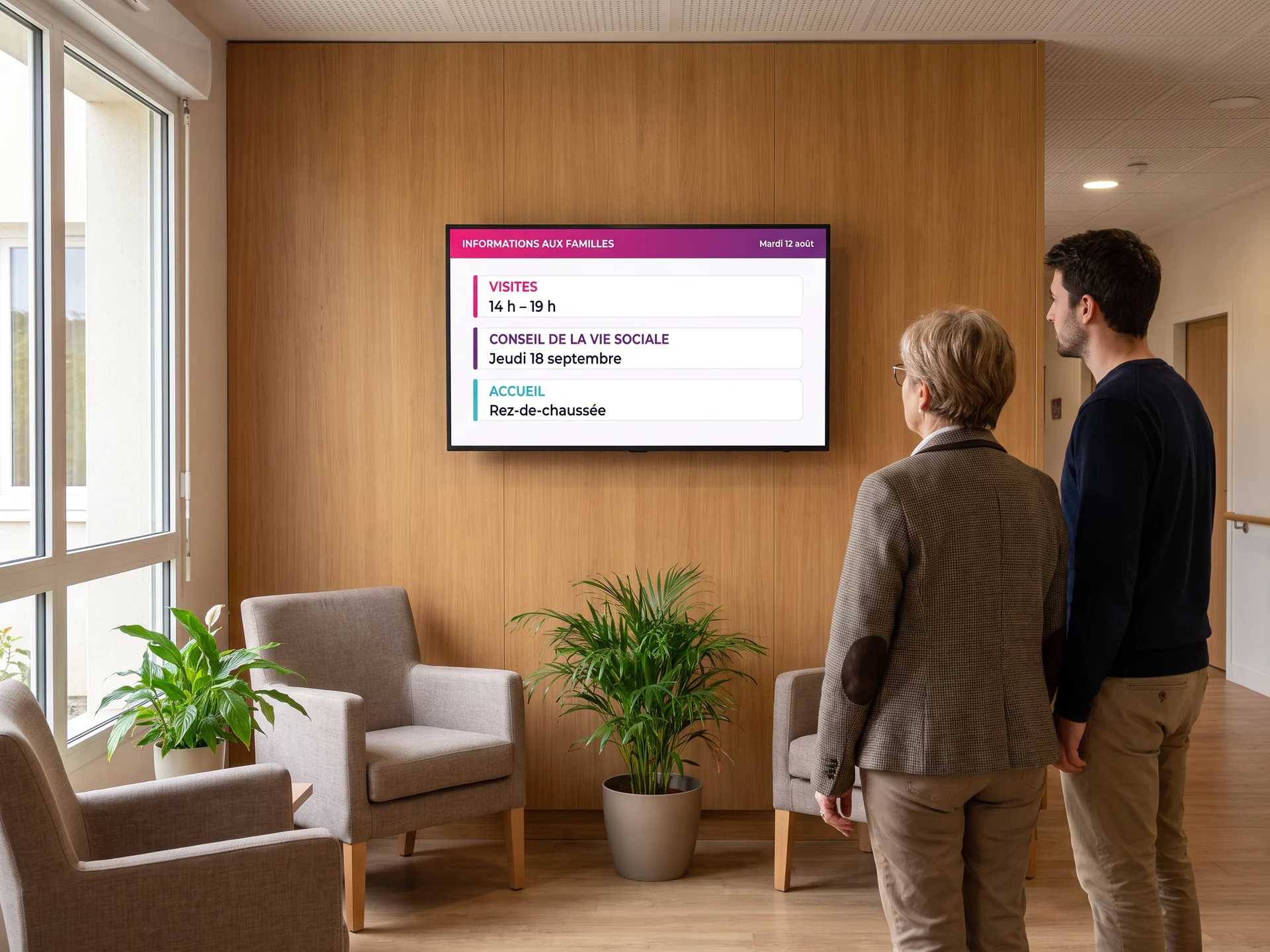 &Eacute;cran d&rsquo;information des familles dans le hall d&rsquo;un &eacute;tablissement pour personnes &acirc;g&eacute;es, indiquant les horaires de visite