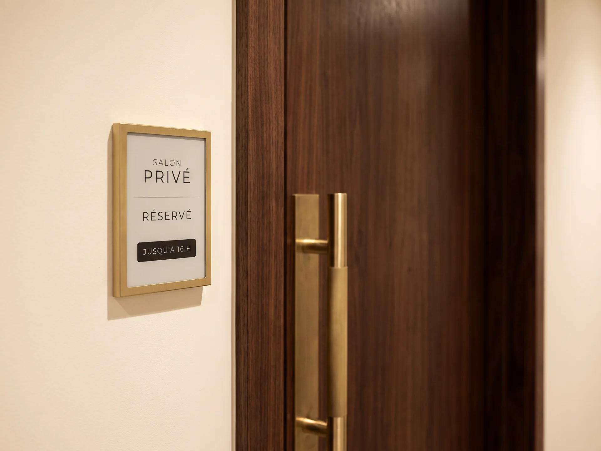 Petite dalle e-paper mate dans un cadre laiton, &agrave; c&ocirc;t&eacute; d&rsquo;une porte en noyer