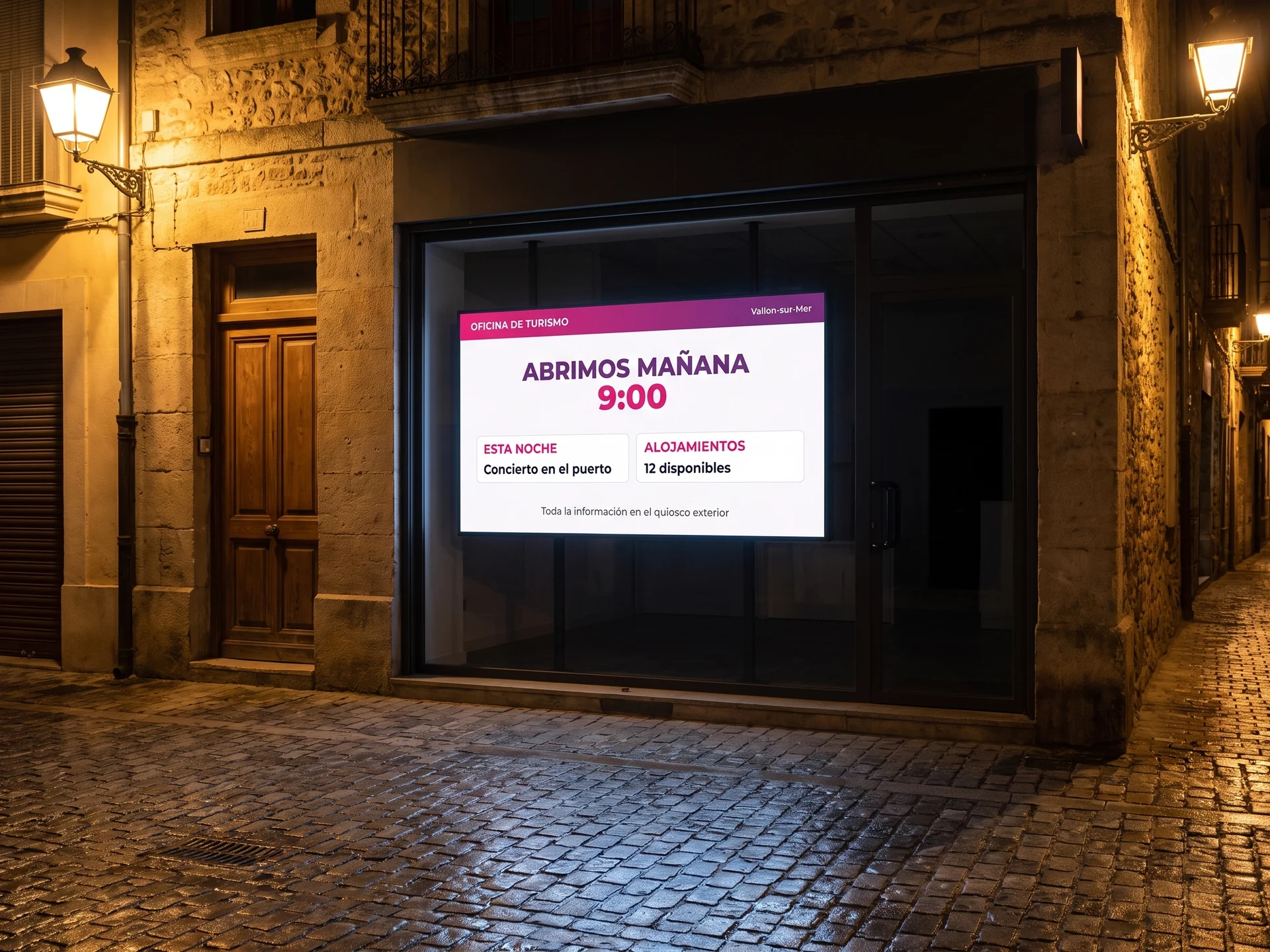 Pantalla de cartelería digital en el escaparate de una oficina de turismo cerrada de noche, con la hora de apertura y los eventos de la tarde