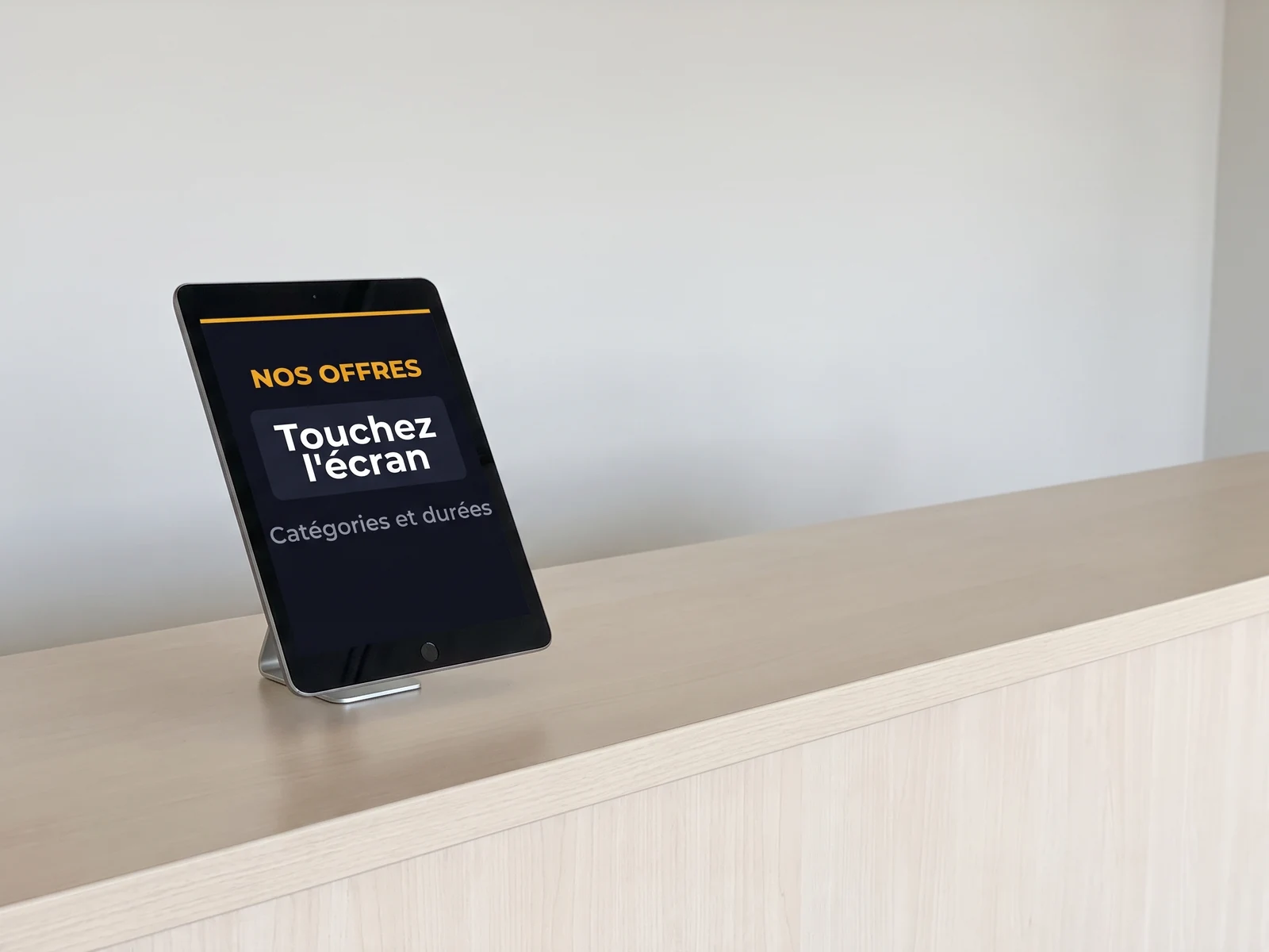 Tablette tactile en portrait sur le comptoir d'une agence de location, invitant le client à consulter les offres