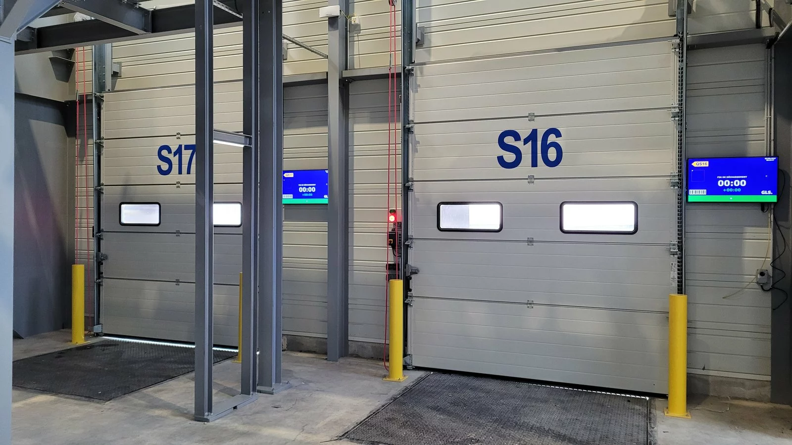 Portes de quai S16 et S17 du hub GLS, chacune surmontée d'un écran affichant le numéro de quai et l'heure de fin de déchargement