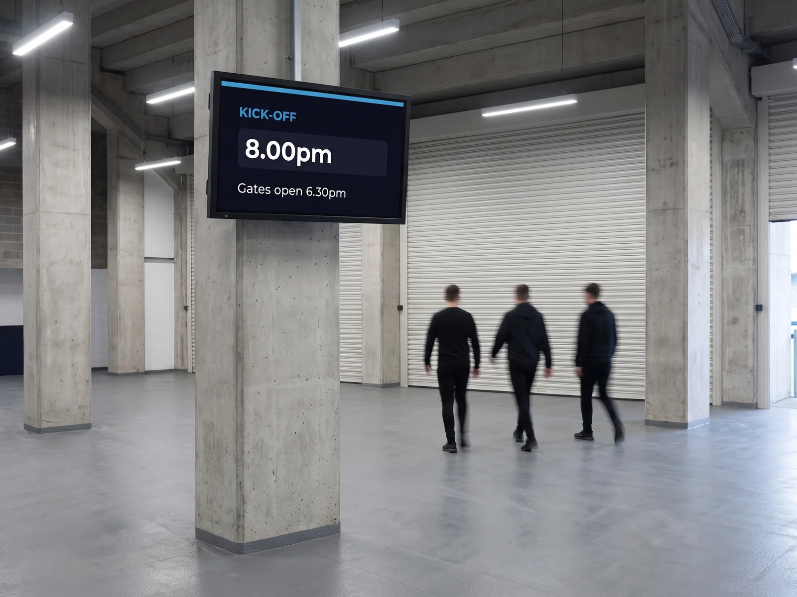 Wall-mounted screen on a stadium concourse showing kick-off and gate opening times