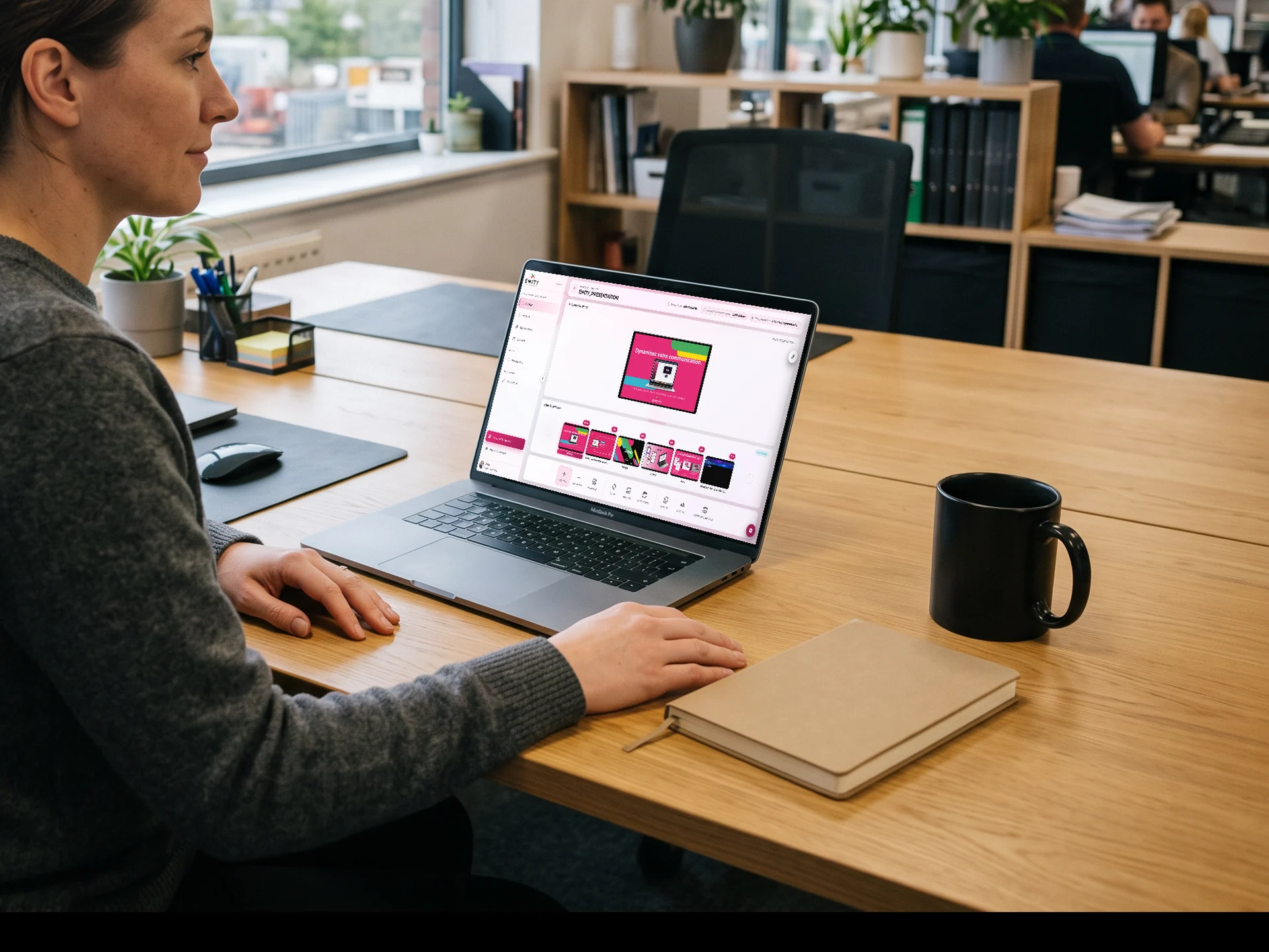 Chargée de communication assise à son bureau, la plateforme E-MANAGER ouverte sur son portable, en train de préparer une liste de diffusion