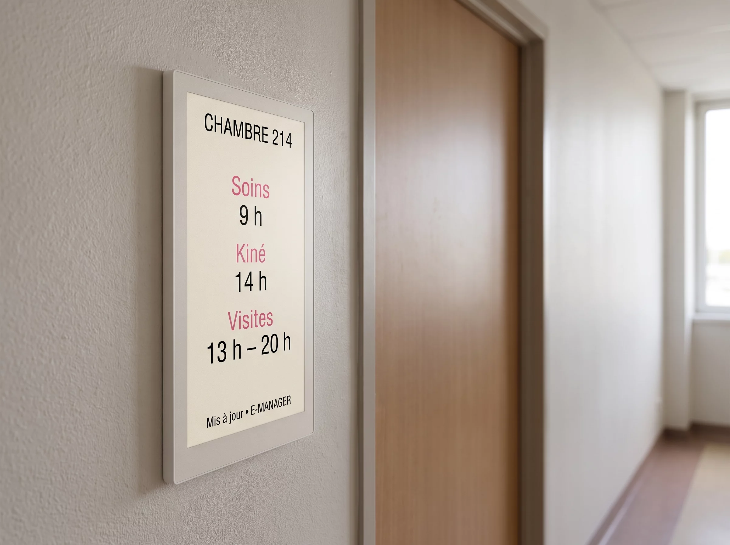 Dalle à encre numérique posée à côté d'une porte de chambre d'hôpital, indiquant le numéro de chambre et les horaires de soins et de visites