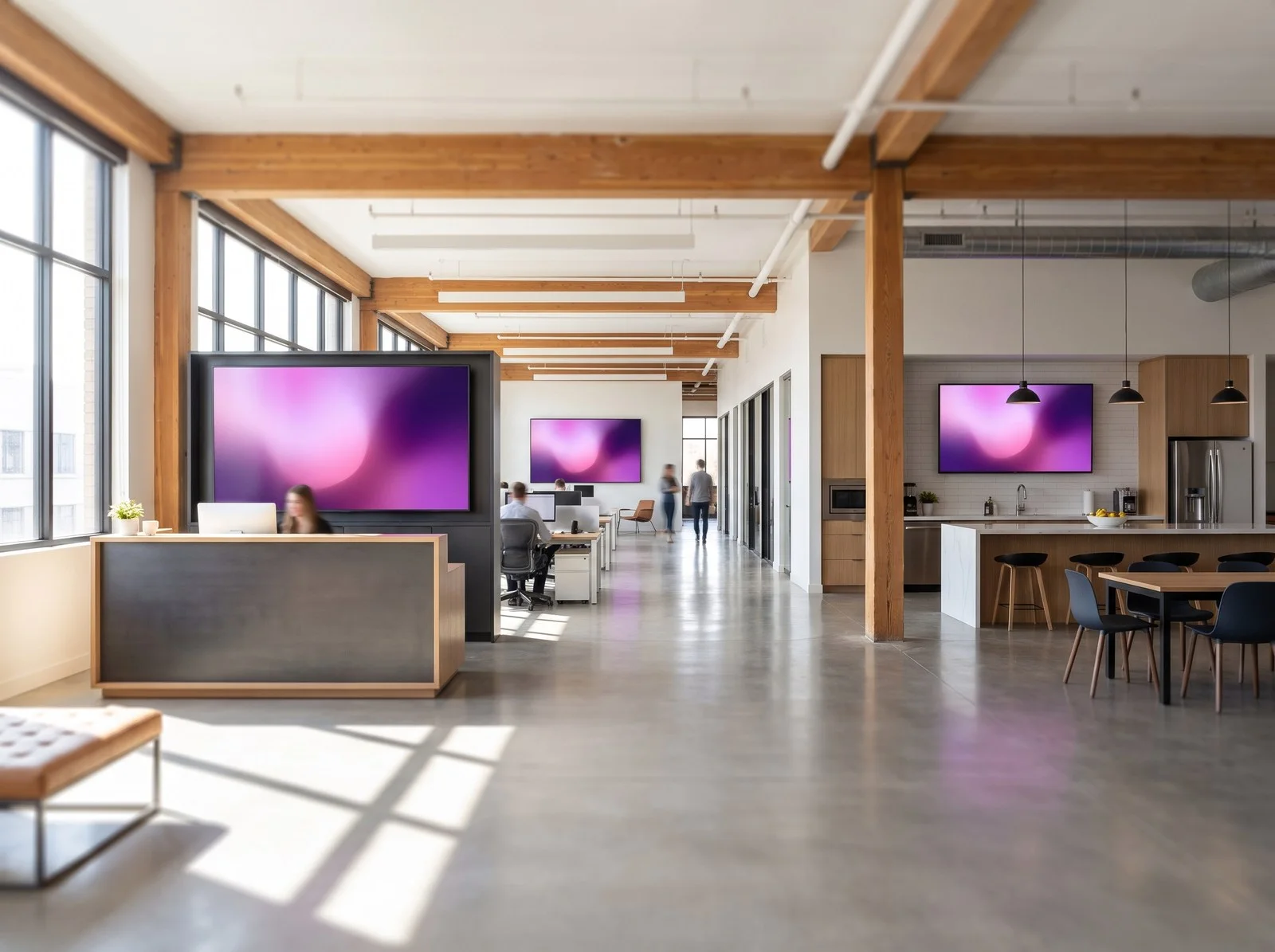 Plateau de bureaux en bois clair où plusieurs écrans diffusent des contenus coordonnés