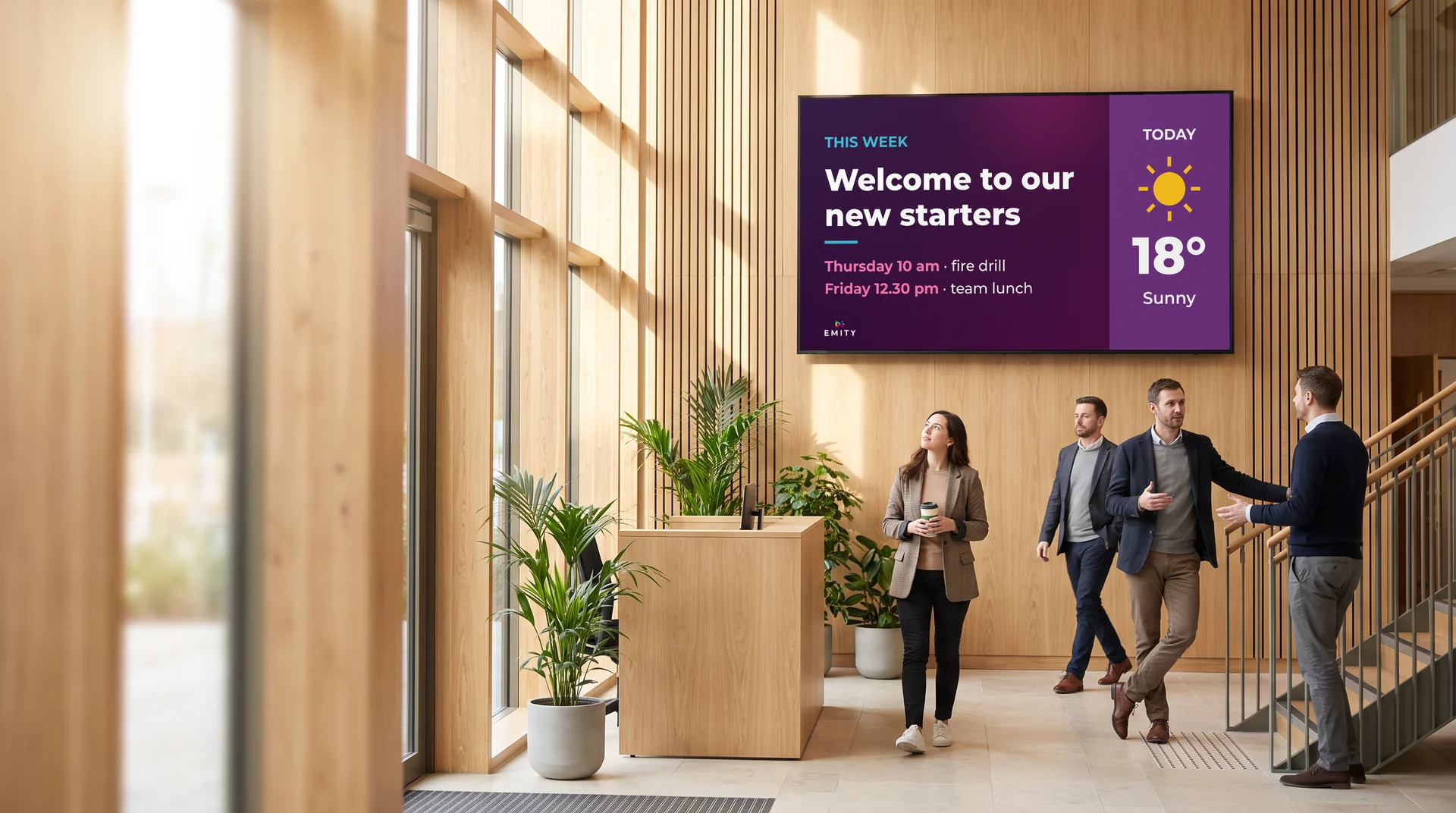 Light-wood company lobby: wall screen welcoming new starters