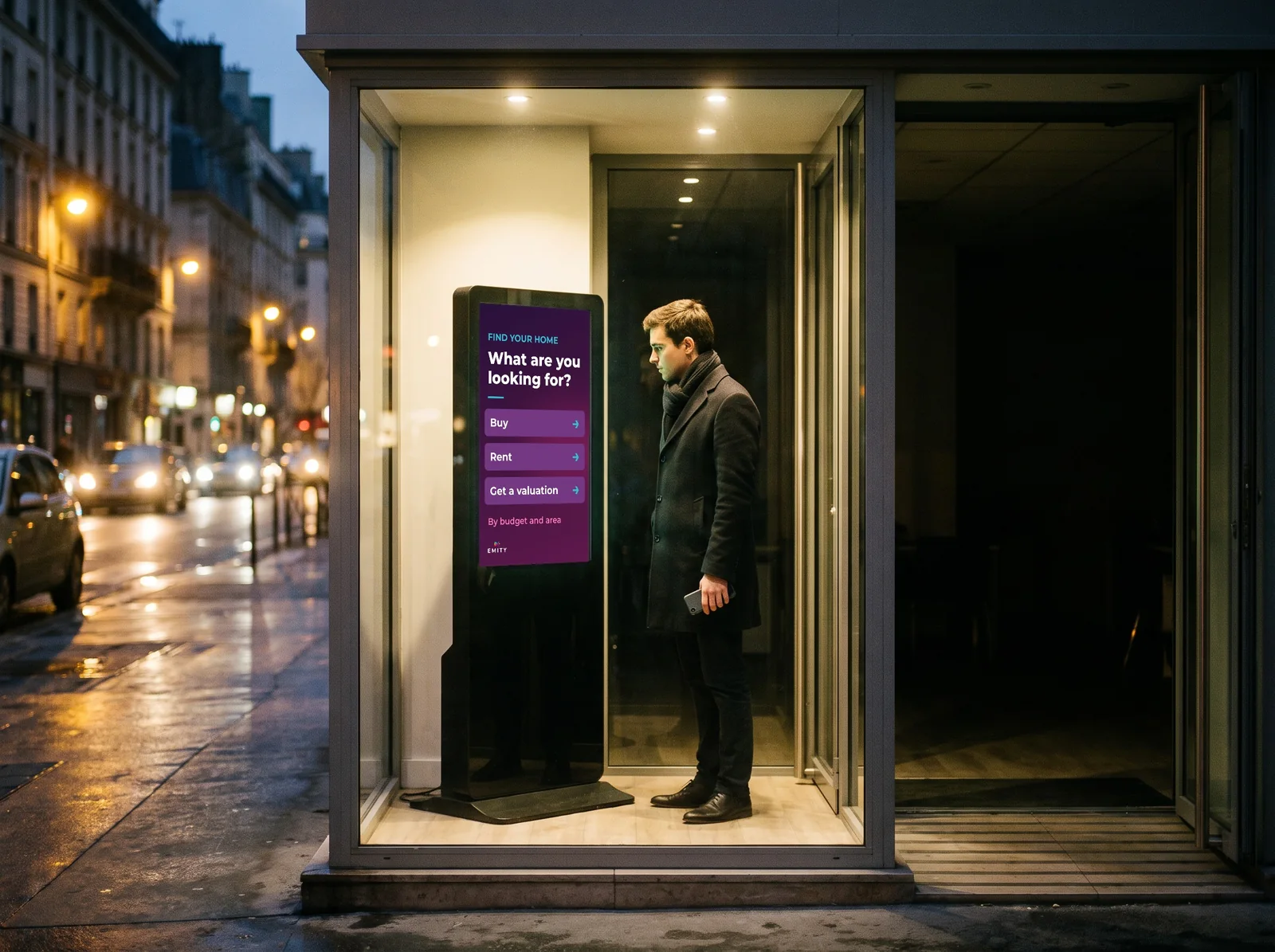In the evening, a passer-by searches for a property on the touch kiosk in the entrance of a closed agency: buy, rent or get a valuation