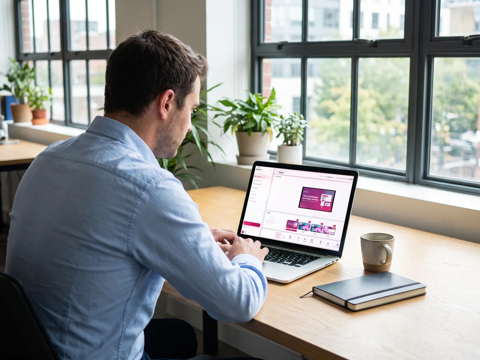 Employee at his desk scheduling a poster in E-MANAGER on his laptop