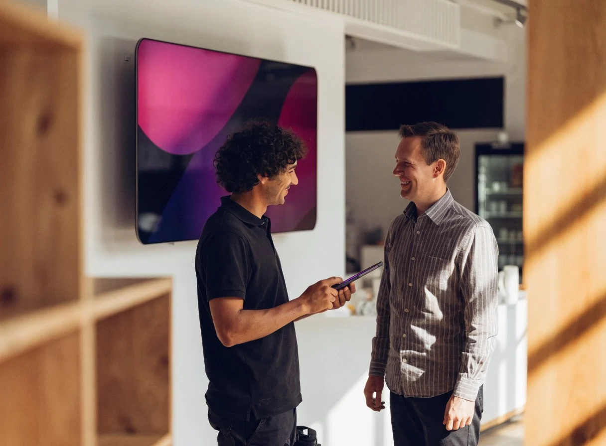 Technicien d'un revendeur certifié qui échange avec un client devant un écran installé