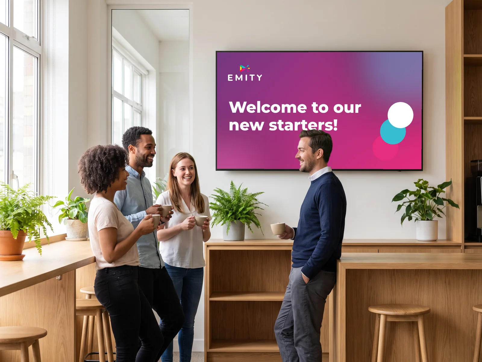 Company coffee area: colleagues welcome a new starter under the screen greeting new starters