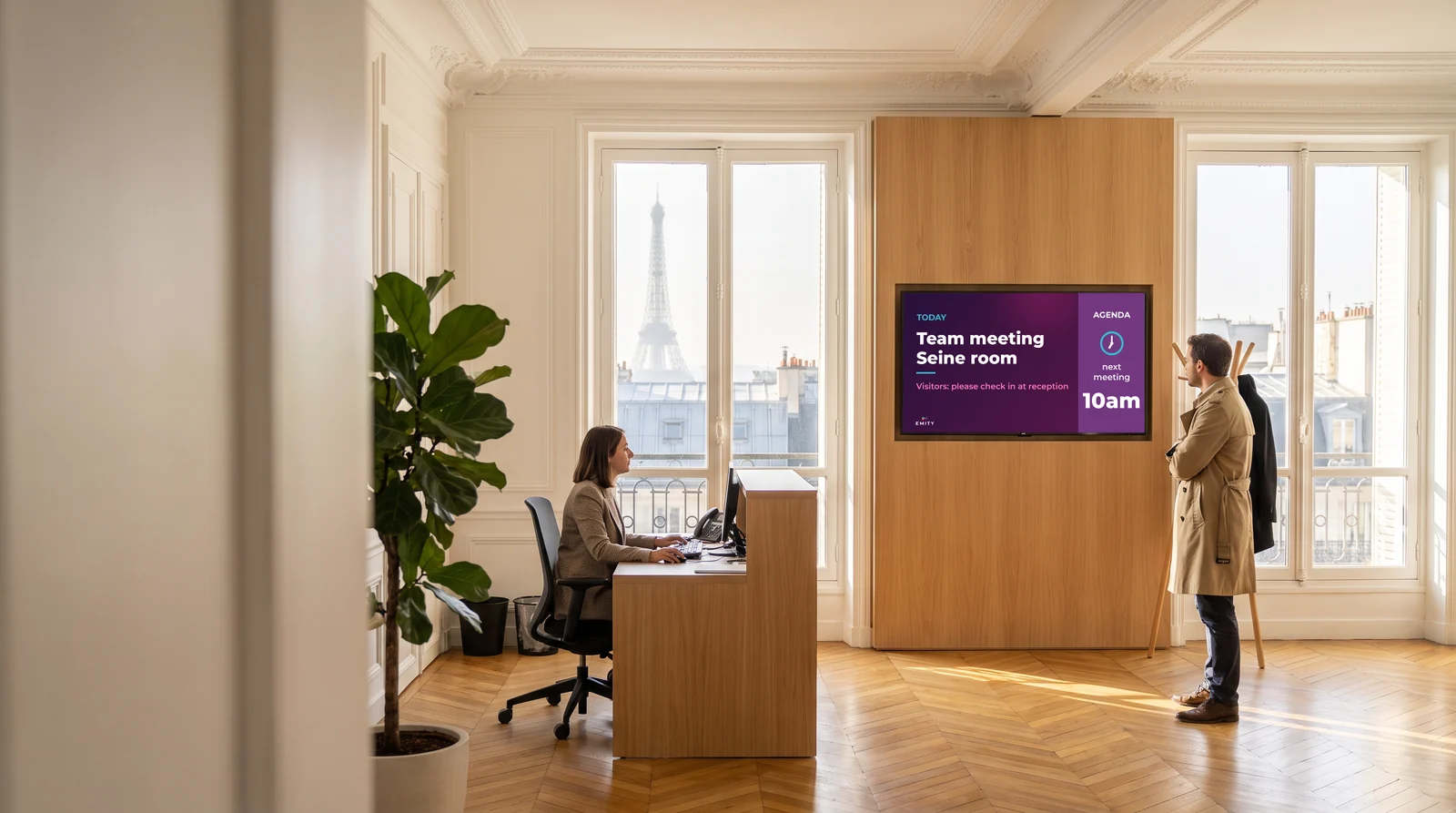 Paris head-office lobby, Eiffel Tower through the window: screen “Today · Team meeting, Seine room · 10am” near reception