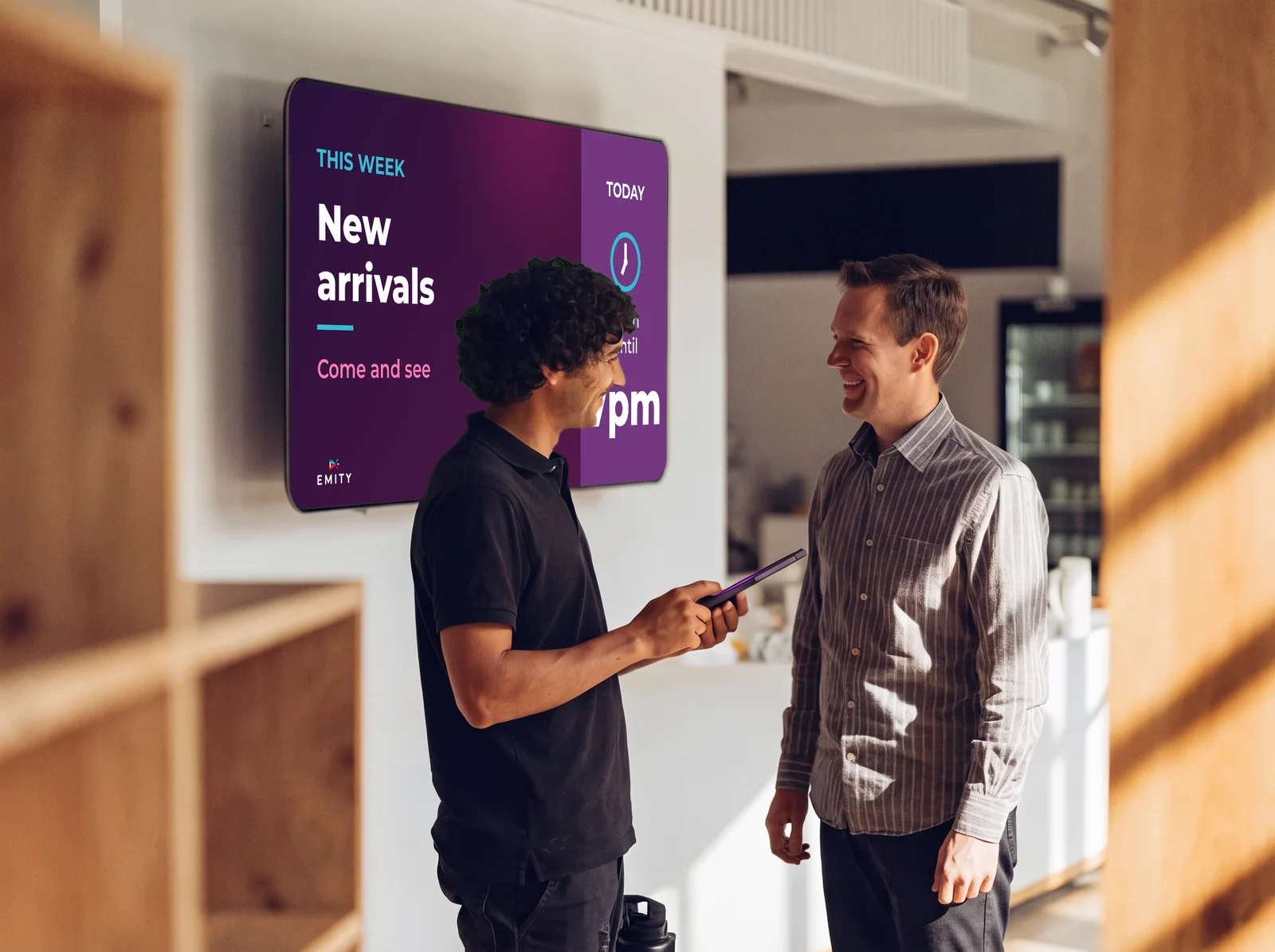 A certified reseller's technician, tablet in hand, talking with his customer in front of the shop screen “New arrivals”
