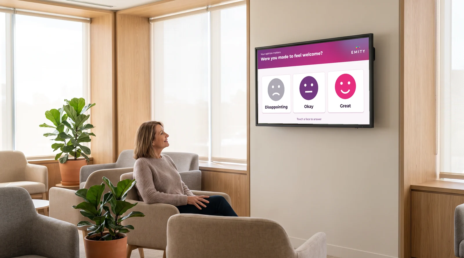 Patient in a waiting room facing a wall screen asking if she was made to feel welcome