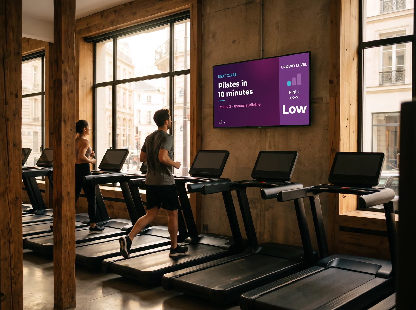 Runners on the treadmills facing the screen announcing the next Pilates class and current crowd level