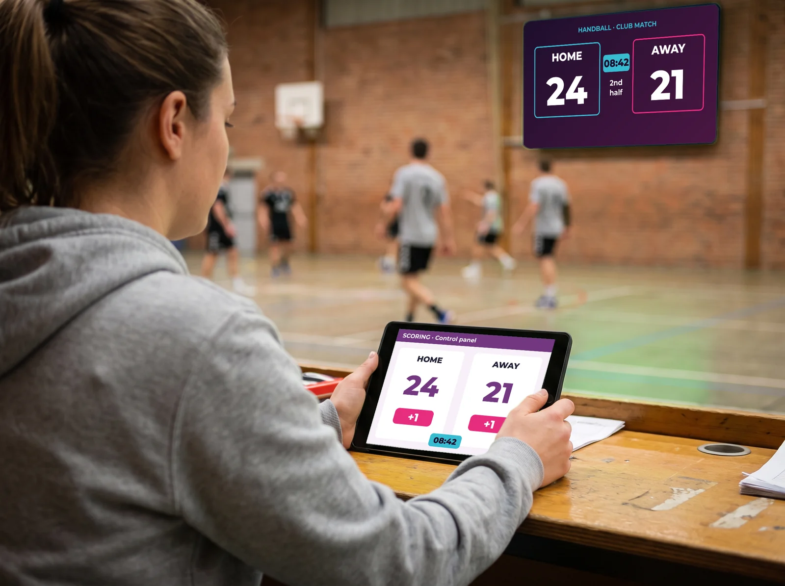 Volunteer at the scorer's table entering the score on the SCORING tablet, shown live on the sports hall screen