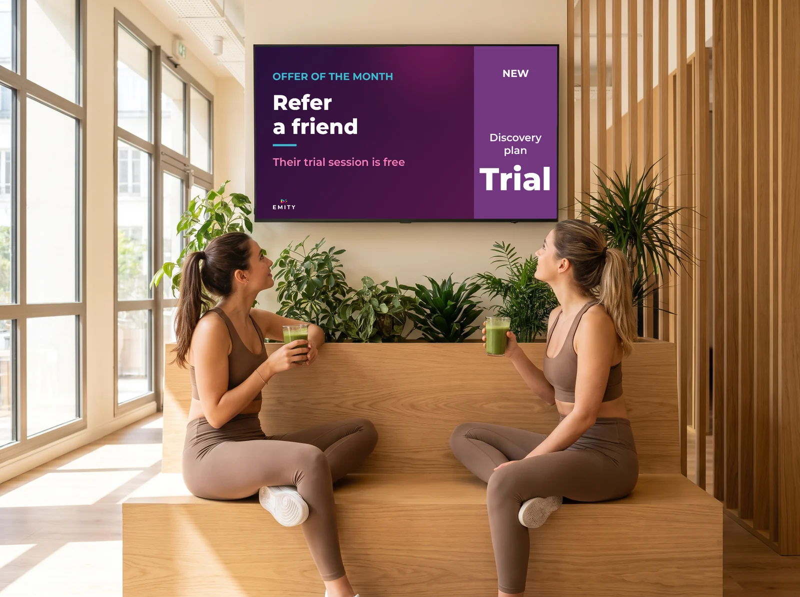 Two members in the club's lounge looking at the screen showing this month's referral offer